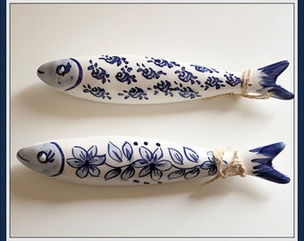 May include: Two white ceramic fish with blue floral designs. The fish are tied together with twine.