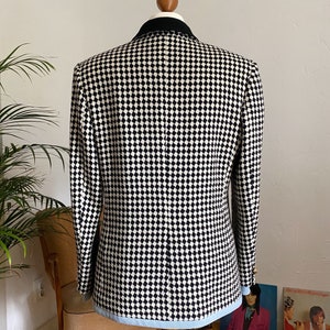 May include: A black and white checked blazer with a blue trim. The blazer has a black velvet collar and gold buttons.