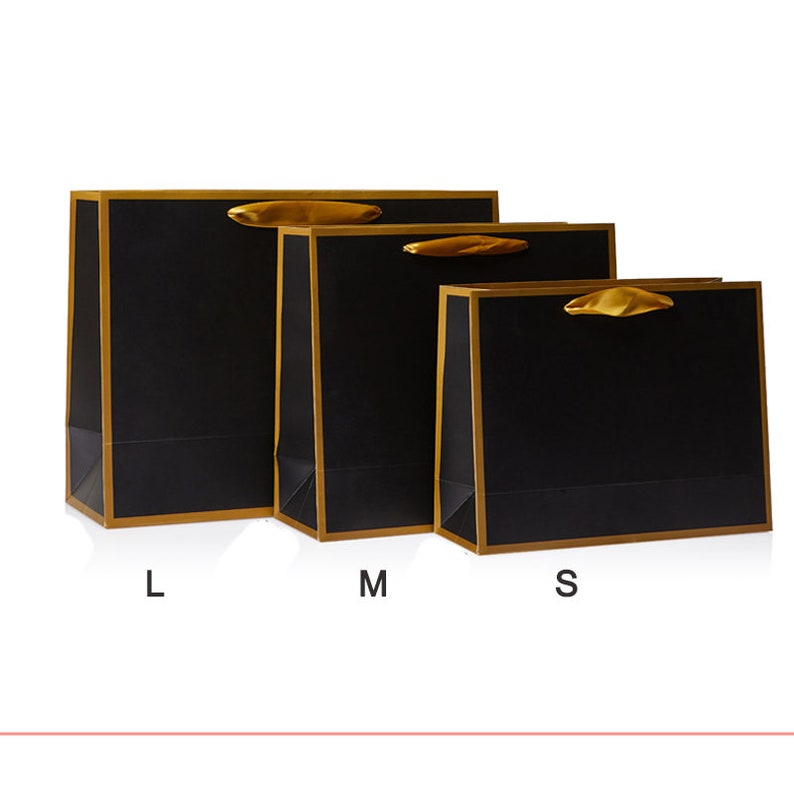 May include: Three black gift bags with gold trim and ribbon handles. The bags are labeled L, M, and S.