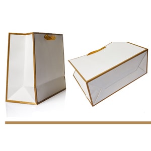 May include: Two white gift bags with gold trim and a gold ribbon handle. The bags are shown from different angles.