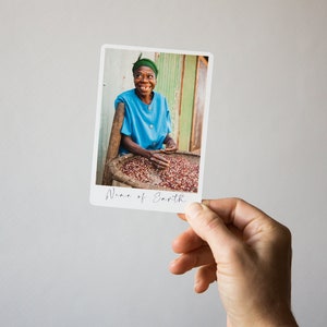 May include: A woman in a blue shirt and green headwrap smiles while sorting red coffee beans in a basket. The image is captioned "Wine of Earth."
