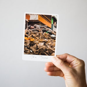 May include: A black and white photo of a man lying on a pile of rubble. The photo is titled "The Tower".