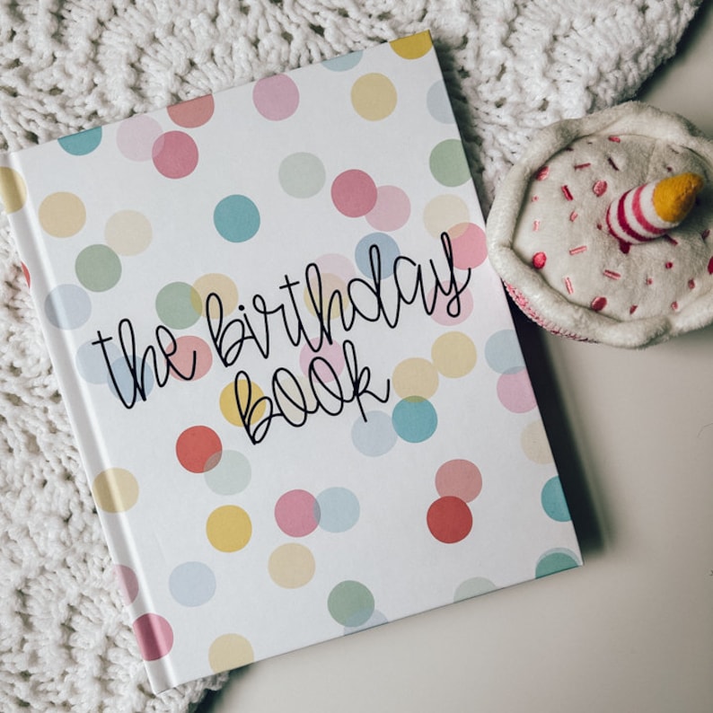 Birthday memory book covered in green, pink, blue, and yellow polka dots titled The Birthday Book in black text.