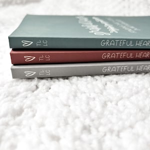 Side view of paperback journals has a heart, TLLC, and Grateful Heart printed on the spine