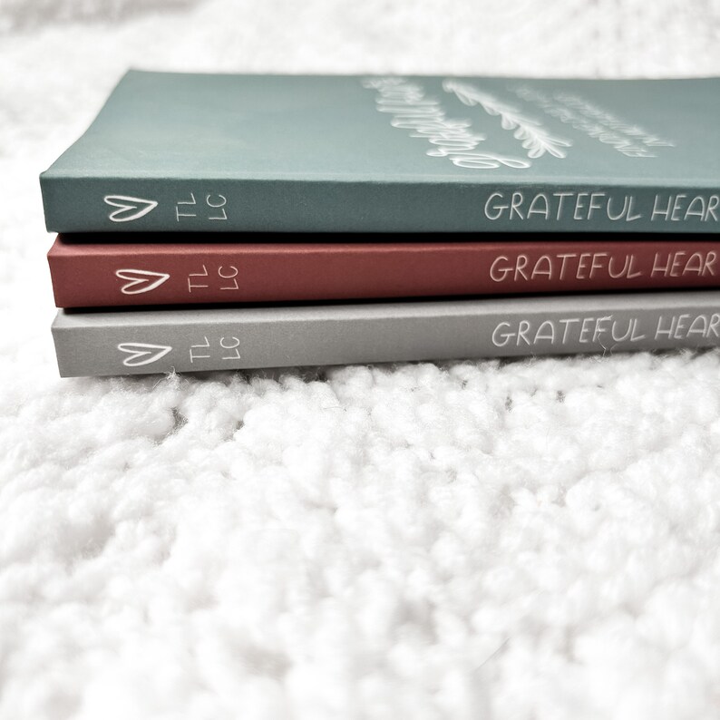 Side view of paperback journals has a heart, TLLC, and Grateful Heart printed on the spine