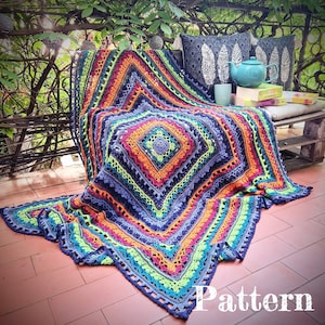 Peut inclure: Une couverture en crochet colorée avec un motif géométrique dans des tons de bleu, vert, orange et rose. La couverture est drapé sur un banc en bois avec des coussins et une théière.