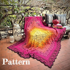 Könnte beinhalten: Eine gehäkelte Wolldecke mit einem farbenfrohen Ombre-Design in den Farben Rosa, Orange und Gelb. Die Decke liegt über einer Holzbank mit Kissen und einer Teekanne.