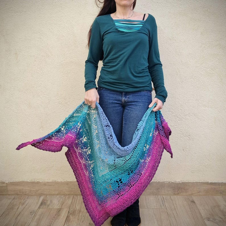 Pu&ograve; includere: Uno scialle all'uncinetto con un gradiente di colori rosa, blu e verde. Lo scialle &egrave; di forma triangolare e presenta un delicato motivo a pizzo.