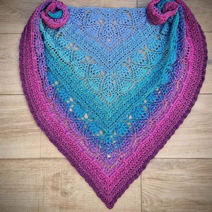 Pu&ograve; includere: Uno scialle all'uncinetto con un gradiente di colori dal viola al blu. Lo scialle presenta un delicato motivo a pizzo ed &egrave; realizzato con un filato morbido.