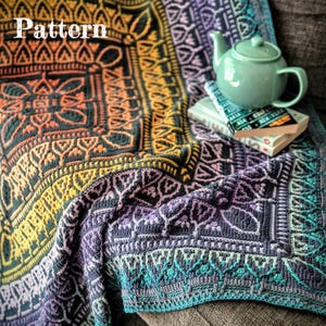 Può includere: Una coperta colorata e fantasia con la parola "Pattern" in alto a sinistra. La coperta presenta un design geometrico con sfumature di arancione, giallo, viola e verde acqua. Una teiera verde e dei libri sono appoggiati sulla coperta.