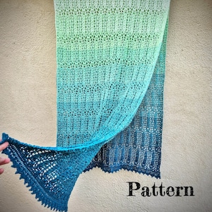 Op de afbeelding: Een gebreide sjaal in tinten blauw en groen, met een delicaat open patroon. De sjaal is gedrapeerd en toont het ingewikkelde ontwerp en de geschulpte rand. Het woord "Pattern" is zichtbaar in de afbeelding.