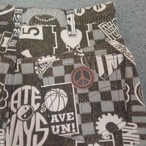 May include: Close-up of a pair of shorts with a brown and white checkered pattern. The shorts feature various graphics, including a basketball, a peace symbol, and the words "ATE WAYS" and "HAVE FUN!"