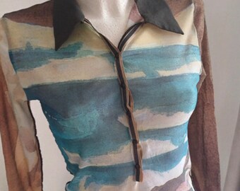 May include: A long-sleeved, sheer, brown, blue, and white shirt with a watercolor print of clouds and sky. The shirt has a black collar and a brown button placket.