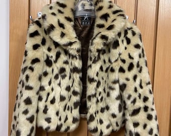 May include: A cropped faux fur jacket with a leopard print pattern. The jacket has a brown lining and a zipper closure.