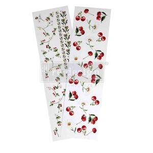 May include: Three white decorative transfer sheets with floral and fruit designs. One sheet features a vertical pattern of small red cherries and green leaves. Another has a pattern of cherries and white daisies. The third sheet has a floral pattern.