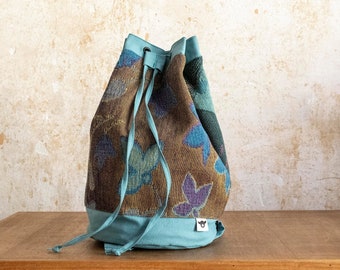 kleiner Bucket Bag Rucksack aus gemustertem Polsterstoff und türkisfarbenem Canvas mit verstellbaren Tragegurten, Ösen und Bindebändel