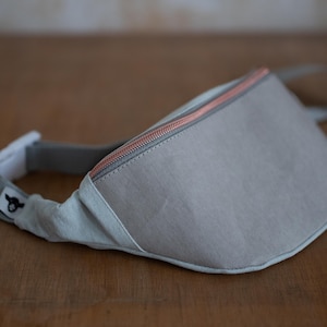 Gürteltasche Bauchtasche Hip-Bag heller Jeansstoff Vorderteil aus grauem Waschpapier, roségoldener Reißverschluss, zwei Reißverschlussfächer