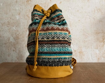 small bucket bag backpack made of colorful patterned wool fabric and yellow cotton canvas with adjustable shoulder straps, eyelets and tie straps