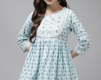 May include: A light blue cotton tunic top with a floral print and white embroidery around the neckline. The top has a gathered waist and a lace trim around the neckline and sleeves.