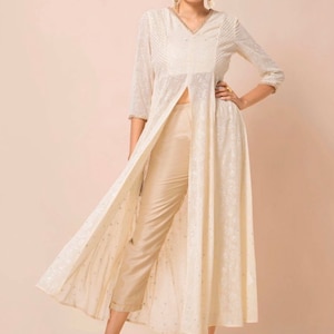 May include: A white long-sleeved tunic with a front slit and delicate embroidery. The tunic is paired with beige trousers.