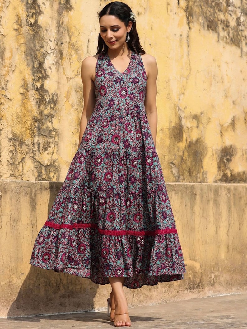 May include: A blue and pink floral print maxi dress with a halter neckline and tiered skirt. The dress has a ruffled hem and is made of a lightweight fabric.