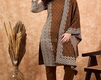 May include: A brown two-piece outfit with a patterned design. The outfit includes a long-sleeved tunic and matching trousers. The tunic features a decorative border and a V-neckline. The outfit is paired with brown flats.