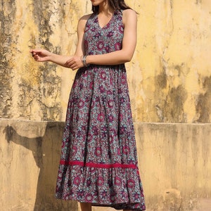 May include: A blue and pink floral print maxi dress with a halter neckline and a tiered skirt. The dress has a red trim at the hem.