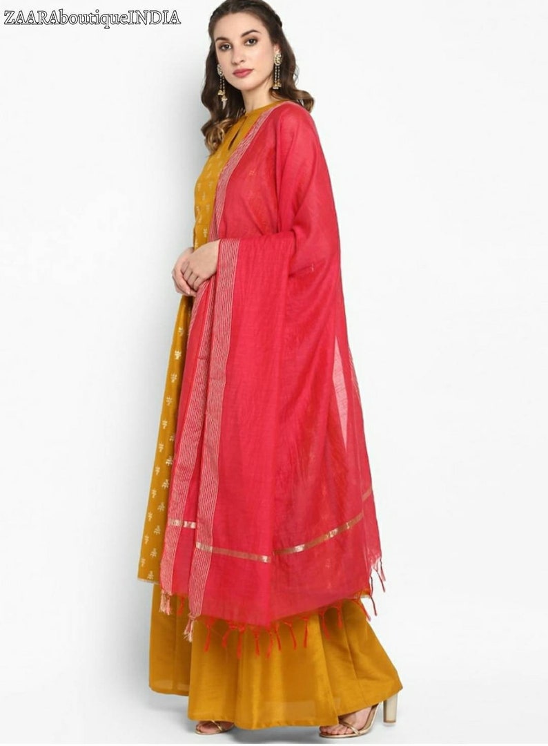 May include: A mustard yellow long dress with a floral pattern and a pink dupatta with gold trim. The dupatta has a fringe border.