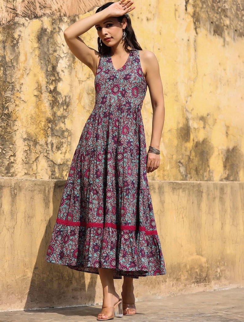 May include: A sleeveless maxi dress with a floral print in shades of blue, pink, and purple. The dress has a tiered skirt and a ruffled hem.