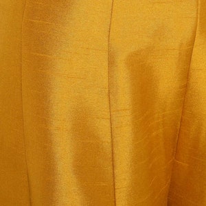 May include: Close-up of a mustard yellow fabric with a subtle texture. The fabric has a smooth, silky feel.