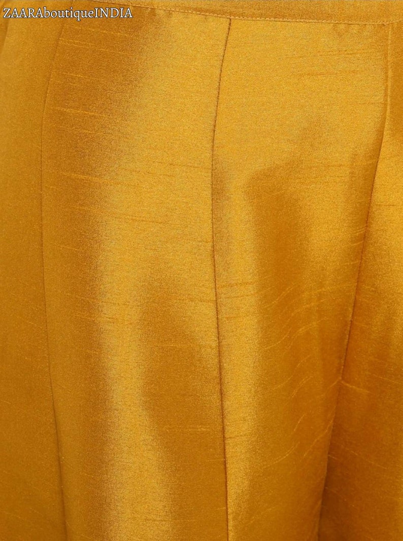 May include: Close-up of a mustard yellow fabric with a subtle texture. The fabric has a smooth, silky feel.
