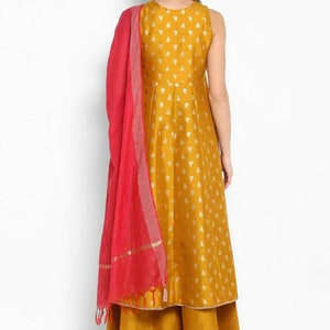 May include: A mustard yellow sleeveless kurta with a gold print and a matching palazzo pant. The kurta has a round neckline and a pink dupatta with gold trim.