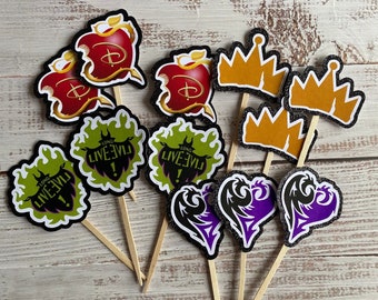 Pode incluir: Um conjunto de 10 toppers para cupcakes com personagens e símbolos do filme da Disney Descendants. Os toppers incluem uma maçã vermelha com uma coroa, um coração roxo com asas, uma chama verde com o texto "Long Live Evil", e uma coroa dourada.