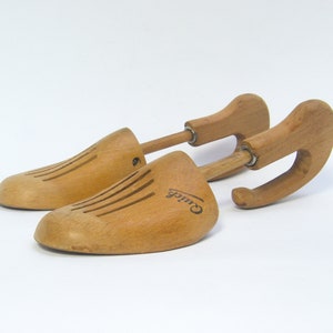 May include: Pair of wooden shoe trees with a curved handle and a grooved design. The shoe trees are labeled "Craddock".