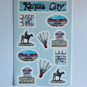 Pode incluir: Uma folha de adesivos com v&aacute;rios marcos e s&iacute;mbolos de Kansas City, incluindo o horizonte da cidade, uma est&aacute;tua de um cavaleiro a cavalo, um est&aacute;dio e um volante de badminton. A folha tamb&eacute;m inclui o texto "Kansas City" e "Western Auto".