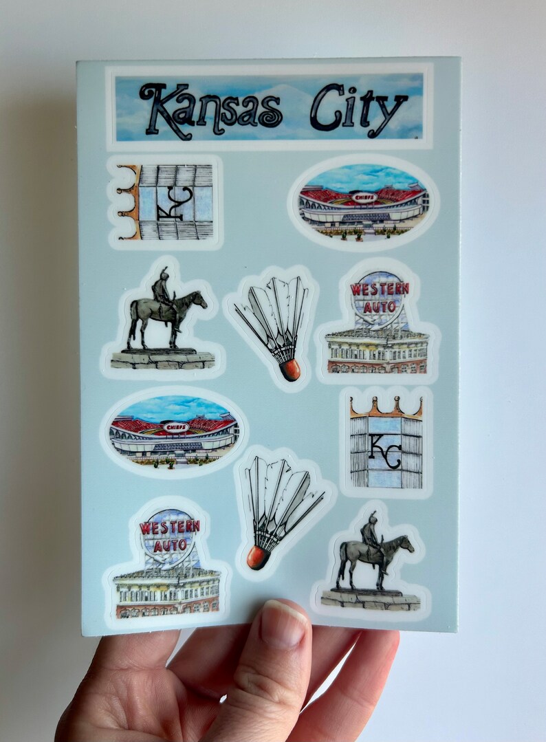 Pode incluir: Um conjunto de nove adesivos com v&aacute;rios marcos e s&iacute;mbolos de Kansas City, Missouri. Os adesivos s&atilde;o impressos em papel branco com fundo azul claro. Os adesivos incluem um est&aacute;dio, uma est&aacute;tua de um cavaleiro a cavalo, um volante e uma placa para Western Auto.