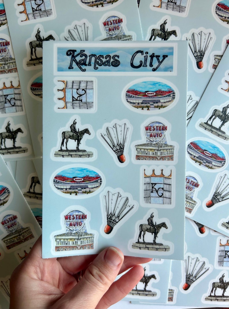 Pode incluir: Uma folha de adesivos com v&aacute;rias imagens relacionadas a Kansas City, incluindo o horizonte da cidade, um est&aacute;dio, uma est&aacute;tua de um cavaleiro a cavalo e um volante. O texto "Kansas City" est&aacute; impresso na parte superior da folha.