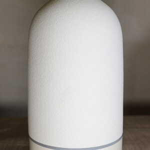 May include: White ceramic essential oil diffuser with a textured surface. It has buttons for light, mist, and timer settings: ON, 15S, 1H, 3H.