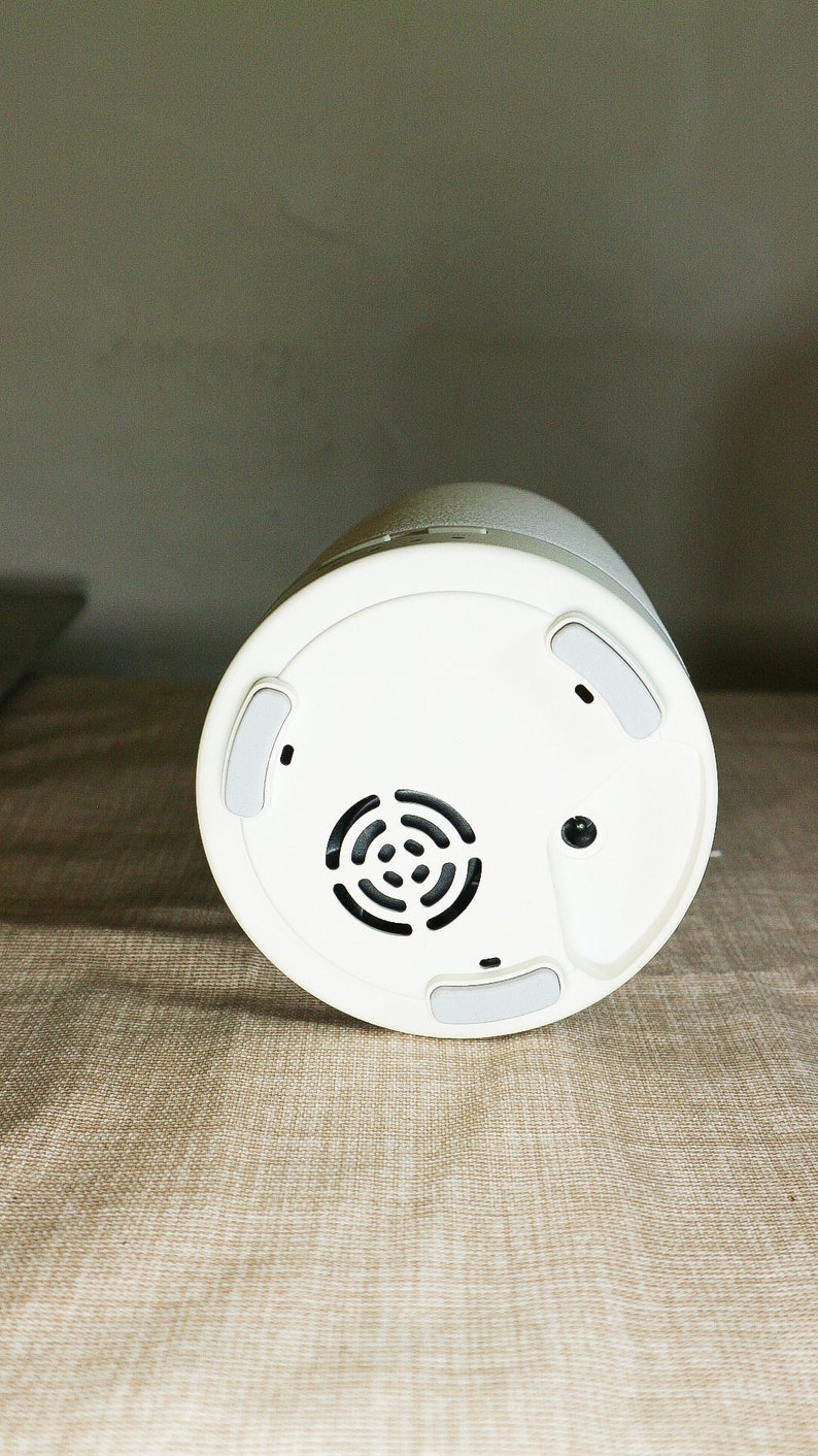 May include: White round speaker with a black speaker grill and four rubber feet on the bottom.