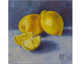 May include: A still life painting of three lemons on a blue background. Two whole lemons are on the left side of the painting, and one lemon is cut into two slices on the right side. The painting is signed "KA 22" in the bottom right corner.