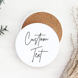 May include: White ceramic coaster with a cork backing. The coaster has the text "Custom Text" written in black cursive.