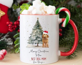 May include: White ceramic mug with a red handle and rim, filled with marshmallows and a candy cane. The mug features a watercolor illustration of a Christmas tree and a poodle wearing a Santa hat. Text reads "Merry Christmas to the Best Dog Mum."