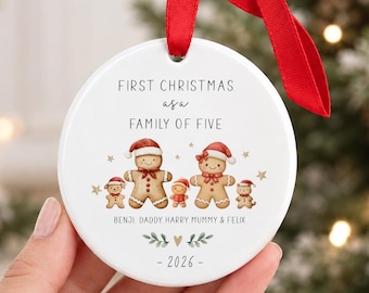 Puede incluir: Un adorno navideño redondo de cerámica blanca con una cinta roja. El texto dice FIRST CHRISTMAS AS A FAMILY OF FIVE, BENJI DADDY HARRY MUMMY & FELIX y 2026. Incluye un gráfico de cinco figuras de pan de jengibre con gorros de Papá Noel.