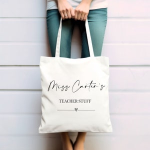 May include: White canvas tote bag with black text that reads "Miss Carter's Teacher Stuff" with a small heart symbol below the text.