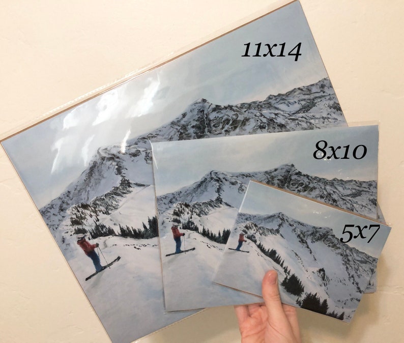 May include: Three different sizes of prints of a snowy mountain scene with a skier in the foreground. The sizes are 11x14 inches, 8x10 inches, and 5x7 inches.