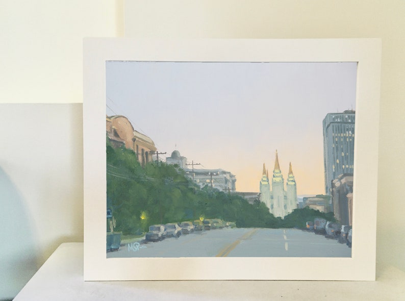 May include: A painting of a city street scene with a view of the Salt Lake Temple in the distance. The street is lined with trees and cars, and the sky is a soft blue.