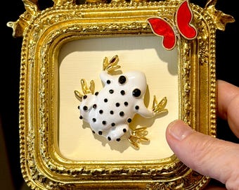 Spilla a forma di rana in smalto incorniciata / Rana a pois bianchi e neri con farfalla rossa / Cornice con fiocco dorato / Decorazione da parete realizzata con gioielli riciclati