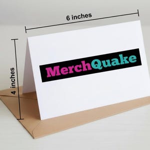 Może przedstawiać: Biała kartka z pozdrowieniami z tekstem "MerchQuake" w kolorze r&oacute;żowym i turkusowym, na czarnym prostokącie. Kartka ma 15 cm szerokości i 10 cm wysokości, spoczywa na brązowej kopercie.