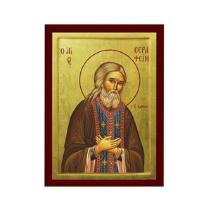 Może przedstawiać: Ikona religijna przedstawiająca Świętego Serafina z Sarowa, rosyjskiego świętego prawosławnego. Ikona jest namalowana w tradycyjnym stylu ze złotymi akcentami i przedstawia świętego z długą białą brodą i niebieską szatą. Tekst "О. С. ФЕИМ" jest napisany cyrylicą u góry ikony.