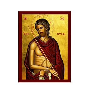 Può includere: Un'icona bizantina che raffigura Gesù Cristo, con una corona di spine e una veste rossa, che tiene un bastone. L'icona è su uno sfondo dorato con testo greco.